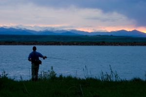 Fly fisherman on a beautiful Colorado summer evening with the Rockies and Mount Evans in the background.